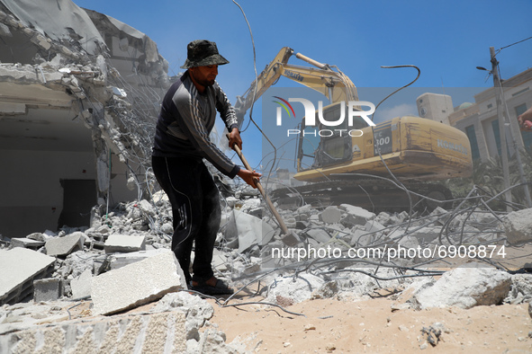 Palestinian workers clear the rubble of buildings, leveled by Israeli bombing during the conflict between Israel and Hamas in May this year,...