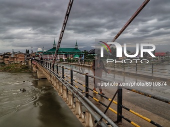 A man holds an Umbrella as he walks over a bridge during rainfall in Sopore, District Baramulla Jammu And Kashmir, India on 28 July 2021. 4...