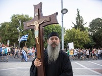 A priest is carrying a cross with Jesus during the demonstration. Hundreds of people, less than the big previous rally, are seen at the Demo...