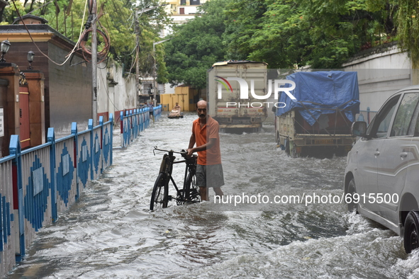 A man with his bicycle struggles in water logged street in Kolkata, India, on July 30, 2021. 