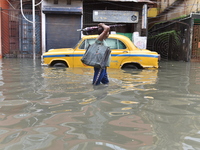 People wade through a waterlogged street  in Kolkata, India, on July 30, 2021. (