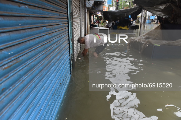 A shopkeeper is seen unlocking his shop as the locks are completely under the water in Kolkata, India, on July 30, 2021. 
