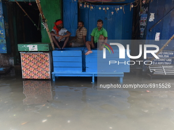 Labourers are seen sitting on boxes in the water logged street in Kolkata, India, on July 30, 2021. (