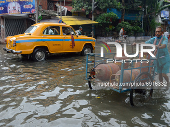 A worker carries LPG gas cylinder amidst a flooded street in Kolkata , India , on 30 July 2021 .LPG gas cylinder prices were hiked over 140...
