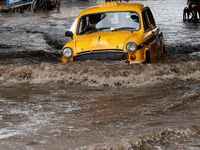 A  yellow Ambassador taxi  drives through a flooded street at the Heavy monsoon rains in Kolkata on July 30,2021. (