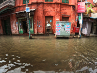 A man look on newspaper at the front  a flooded Street at the Heavy monsoon rains in Kolkata on July 30,2021. (