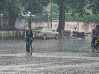 A woman riding a cycle during the rainfall in Dhaka, Bangladesh on July 31, 2021. (