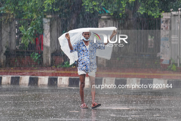 A man covers with polythene to protect himself as he walks during the rainfall in Dhaka, Bangladesh on July 31, 2021 