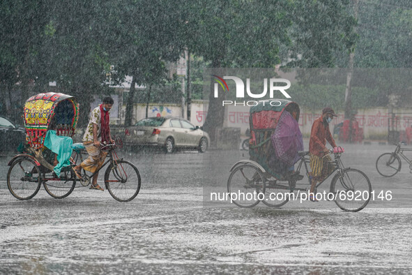 Two-man are pulling rickshaws during the rainfall in Dhaka, Bangladesh on July 31, 2021. 