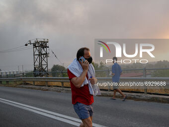 A local resident looks on as a forest fire rages in Varybobi, north of Athens, on August 3, 2021. Residential areas in Athens northern subur...