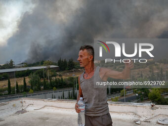 A local resident reacts as a forest fire rages in Varybobi, north of Athens, on August 3, 2021. Residential areas in Athens northern suburbs...