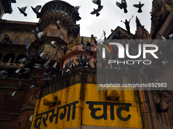 Pigeons fly over the Darbhanga Ghat during rains,on the banks of River Ganges,in Varanasi on July 16,2015. (