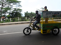 A man wearing a face mask seen riding an eco-friendly electric bicycle cargo for garbage non-organic in Bogor, West Java, Indonesia, on Augu...