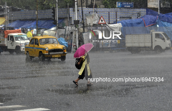 A woman with an umbrella crosses a road during heavy rainfall in Kolkata, India, 10 August, 2021.  