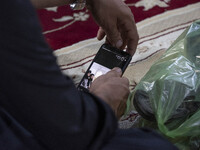 An Afghan refugee man looks at an image of members of the Taliban on his smartphone screen while attending a Moharram mourning ceremony for...