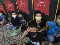An Afghan refugee young boy wearing a protective face mask flashes a Victory sign while attending a Muharram mourning ceremony for praying f...