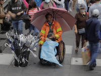 An umbrella seller in a wheelchair in the Historic Centre of Mexico City offers his products after the rains and strong gusts of wind caused...