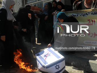 Palestinian women burning an Israeli national flag during a protest marking the anniversary of a 1969 arson attack at Jerusalem's Al-Aqsa mo...