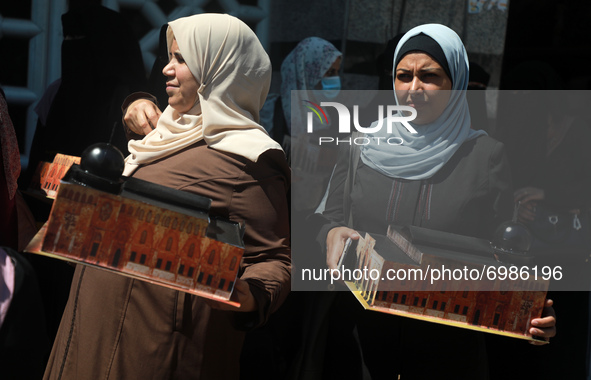 Palestinian women raise a sculpture of Al-Aqsa Mosque during a protest marking the anniversary of a 1969 arson attack at Jerusalem's Al-Aqsa...