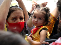 An Afghan woman living in Delhi holds her daughter as she participates in a protest appealing international community to come forward to hel...