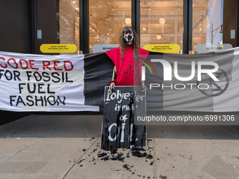 LONDON, UNITED KINGDOM - AUGUST 24, 2021: An environmental activist from Extinction Rebellion with face covered in fake oil protests outside...