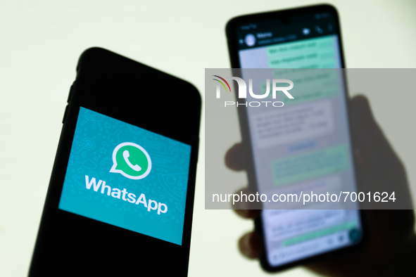 WhatsApp logo displayed on a phone screen and conversation on the WhatsApp displayed on a phone screen in the background are seen in this il...