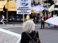 A protester holds up a feminist sign bearing the effigy of the Kurdish philosopher and prisoner Abdullah Ocalan  in Paris, France, on August...