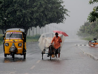 People are seen on the road as they are move wade through in the rain as it rains in the eastern Indian state Odisha's capital city Bhubanes...