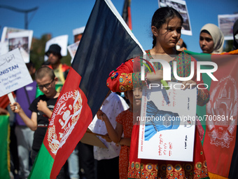 A young afghani girl in traditionnal dress holds an Afghanistan'flag and a placard deppicting a woman wearing a burkha. Dozens of members of...