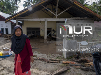 A woman walks in front of her house which was covered in mud after being hit by a flash flood in Rogo Village, South Dolo District, Sigi Reg...