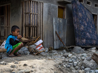 A child is in front of his house which was covered in mud after being hit by a flash flood in Rogo Village, South Dolo District, Sigi Regenc...
