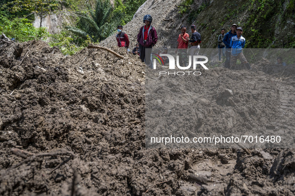 Residents were forced to walk across the Trans Palu-Kulawi Road which was buried by landslide material in Namo Village, Sigi Regency, Centra...