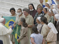 Pope Francis, center, poses for a group photo with nuns holding Brazilian flags during his weekly general audience, held in the Paul VI hall...