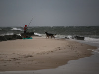 A man and his dog leave a beach as remnants of Hurrican Ida hit Cape May Point, New Jersey, the southern-most tip of the state on September...