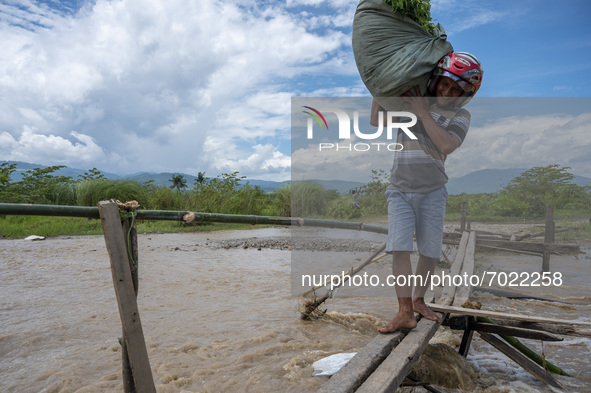 A man carries his belongings through a catwalk to avoid overflowing river water that covers a road in Jono Oge Village, Sigi Regency, Centra...