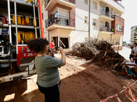 A woman taking a photo of a street filled with mud and derbis the day after flash floods on September 2, 2021 in Les Cases dAlcanar, Spain....