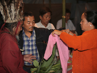 A 90 year-old Lepcha Bomthing (Lepcha priest) wearing a feathered hat chants prayers and uses leaves to bless the sweater of a village girl...