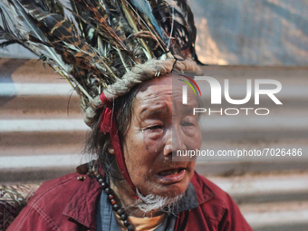A 90 year-old Lepcha Bomthing (Lepcha priest) wearing a feathered hat chants prayers and cries for the dead villagers during an animal sacri...