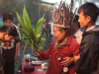 A 90 year-old Lepcha Bomthing (Lepcha priest) wearing a feathered hat chants prayers and uses leaves to bless a village girl during an anima...