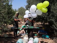 Masked Palestinian supporters of the Hamas movement prepare balloons with “Save Gaza” slogans written on them, near Jabalia refugee camp, ea...