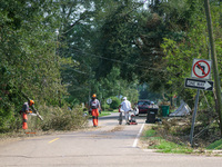 A man pushing his bicycle and pulling a lawnmower is seen walking downtown as clean-up crews work to clear streets of debris following Hurri...