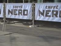 Sunlight, on Friday 24th July 2015, reflecting off the metallic poles, on to the ground, holding small banners which show the Cafe Nero logo...