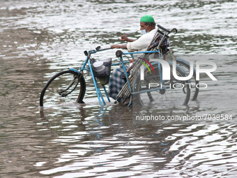 A ficically challenge old man warning surgical facemask against coronavirus try to ride Handicapped Tricycle on the water Logged street afte...