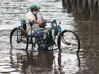 A ficically challenge old man warning surgical facemask against coronavirus try to ride Handicapped Tricycle on the water Logged street afte...