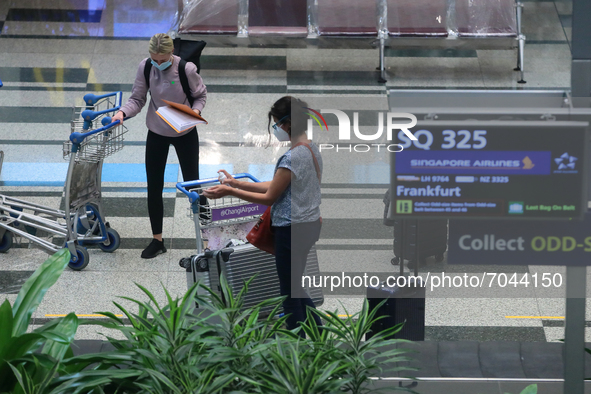 Passengers wearing protective mask collects their bags after arriving on flight SQ 325 from Frankfurt at Changi International Airport on Sep...