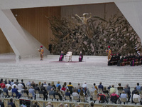 People listen to Pope Francis, white figure on stage, during his weekly general audience in Paul VI hall, at the Vatican, Wednesday, Sept. 8...