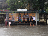 Commuters take shelter under a bus stop during the heavy rain in Yangon, Myanmar on September 9, 2021. On September 7, 2021, the acting pres...