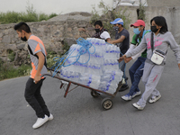 Inhabitants of Cerro del Chiquihuite, in Tlalnepantla, State of Mexico, gather to deliver bottles of water to emergency teams where a landsl...