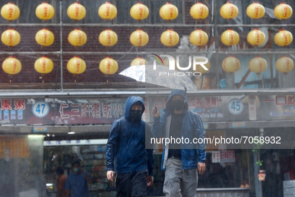 People with umbrellas walk in strings rains and winds in Keelung, as Typhoon Chanthu bringing torrential rains and damaging winds makes land...
