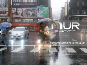 People with umbrellas walk in strong  rains and winds in Keelung, as Typhoon Chanthu bringing torrential rains and damaging winds makes land...